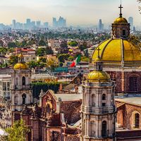 Mexico. Basilica of Our Lady of Guadalupe. Cupolas of the old basilica and cityscape of Mexico City on the far