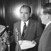 Senator Joseph McCarthy standing at microphone with two other men, probably discussing the Senate Select Committee to Study Censure Charges (Watkins Committee) chaired by Senator Arthur V. Watkins, June 1954