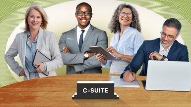 A group of business professionals at a conference table with C-suite sign.